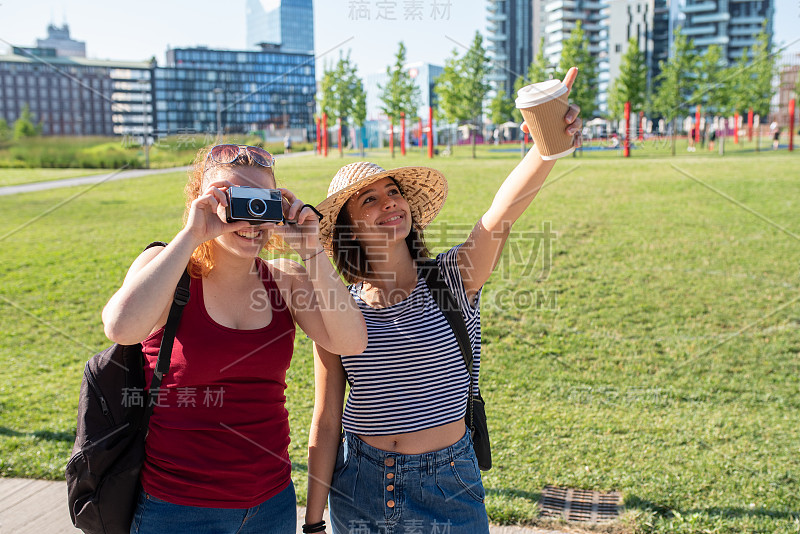 快乐的游客在城市周围探索，用老式相机拍照，看城市风景，笑和喝咖啡，假日概念，积极和探索