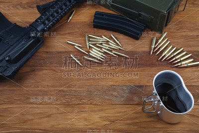 木桌上放着一把步枪和一杯咖啡