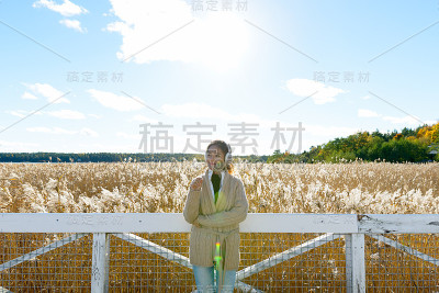 年轻美丽的亚洲女人抱着草近脸，而思考反对风景的秋天芦苇田