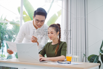 两个年轻的商业同事在办公室用笔记本电脑工作