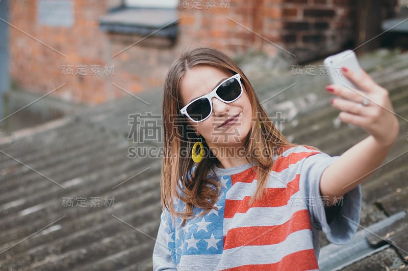 一个最时髦的女孩在一个老院子里拿着手机自拍