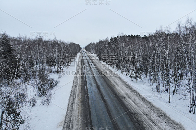 鸟瞰图一辆汽车在冬天的道路在森林。冬天的乡村景观。航拍雪域森林与汽车在道路上。无人机从上面拍下的