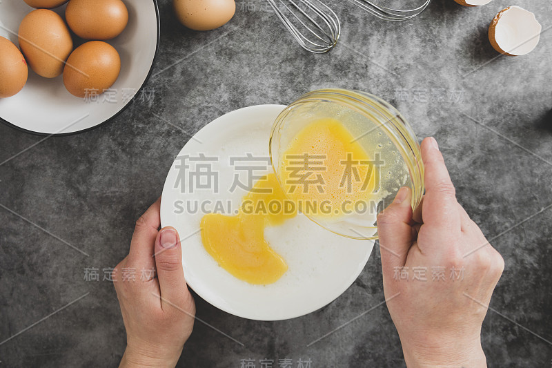 烹饪omlette。女人的手煮煎蛋卷，打破一个新鲜的鸡蛋。黑暗的背景。食物平。