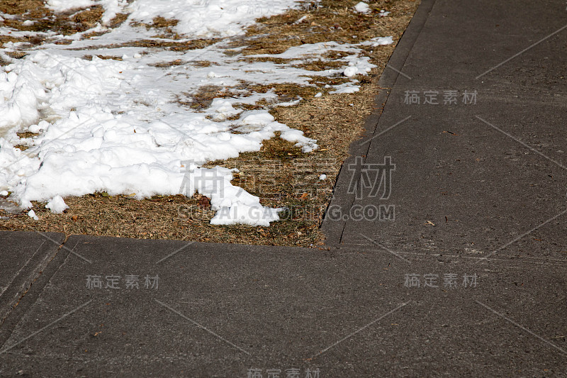 在人行道的角落里，满是枯草和积雪