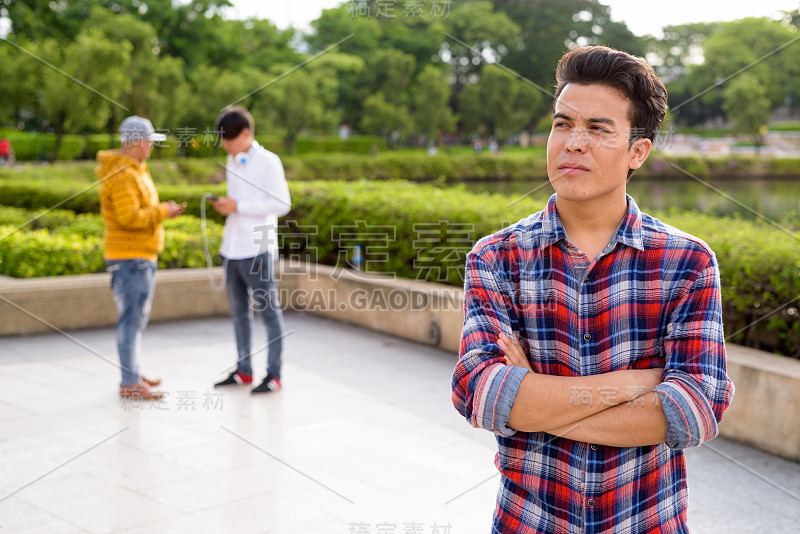 三个年轻的亚洲男人朋友在泰国曼谷的公园放松的肖像