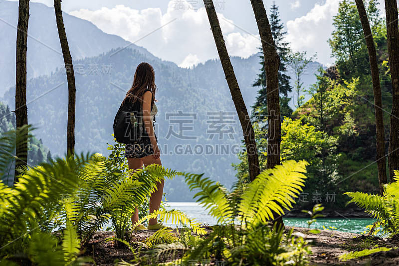 徒步女孩与背包停留和看美丽的风景