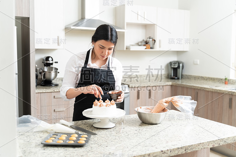 迷人的年轻面包师给蛋糕最后的触摸