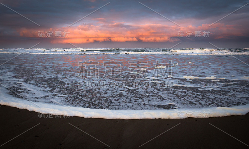 日出映照在海滩上的云彩上