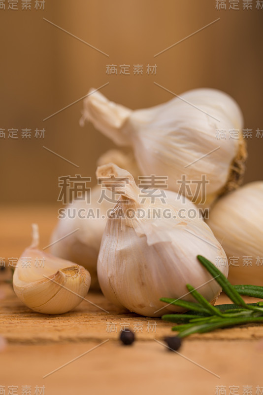 新鲜的大蒜与香料在木背景，百里香和迷迭香。烹饪背景，腌料，近距离。垂直框架