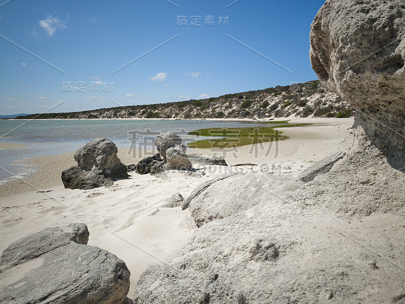 在Langebaan泻湖西岸国家公园的海滩，海岸上有岩石，海滩前有蓝色的水