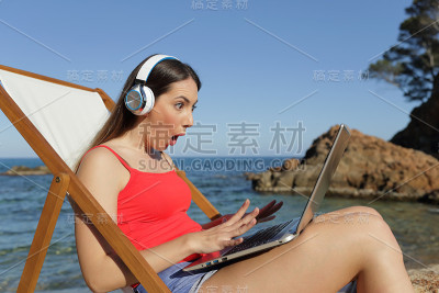 一名在海滩上看笔记本电脑的游客