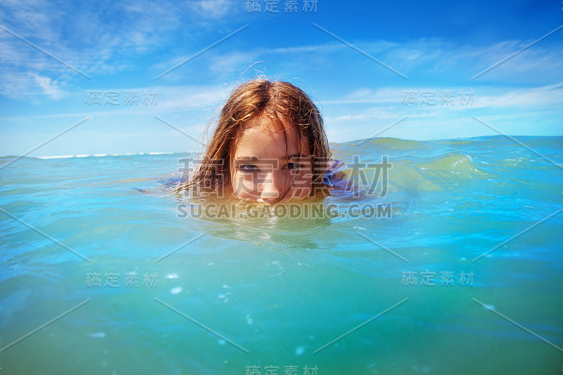 一个女孩在海里游泳的半水下肖像