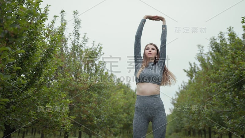 新常态户外运动，年轻健美的运动女性在户外锻炼前伸展身体热身。为了健康和幸福，穿着运动服的女孩在黄昏时