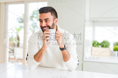 英俊的男人微笑着，享受着清晨的一杯咖啡