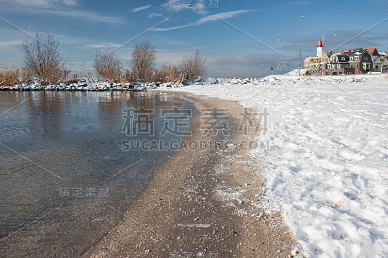 荷兰海滩上覆盖着雪和灯塔Urk的景色