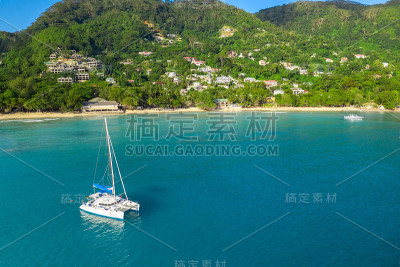 塞舌尔群岛的热带海岸线和蓝色海洋中的白色帆船。