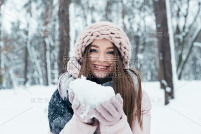 公园里穿着冬装，手里拿着雪的快乐女人的肖像