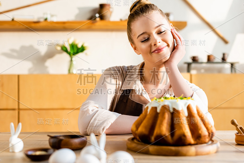 有选择地关注快乐的女人看着复活节蛋糕附近的小兔子装饰雕像