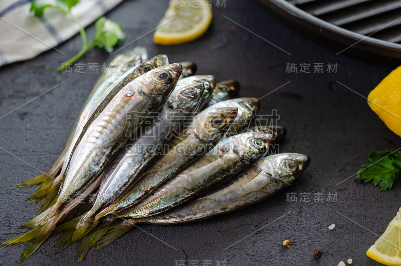 美味新鲜的鱼，芳香的香草，香料和柠檬在黑色的背景。地中海式饮食。