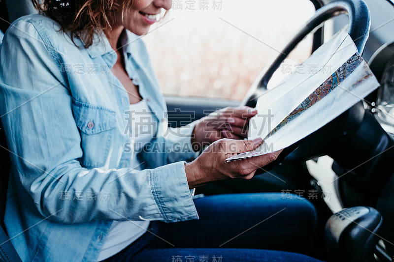 年轻漂亮的女人在车里看地图。旅游的概念