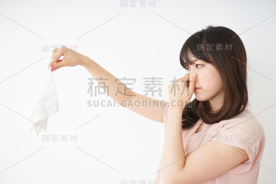 年轻女子闻着脏衣服的臭味
