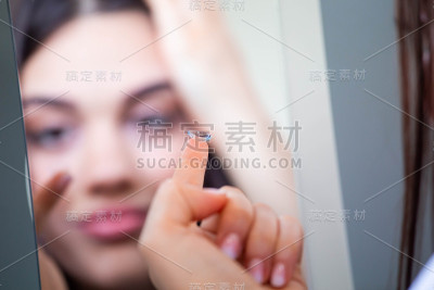 一名年轻女子把隐形眼镜戴进右眼，近处