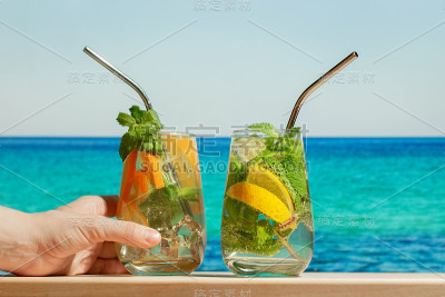 在夏日的海滩上，手握金汤力鸡尾酒