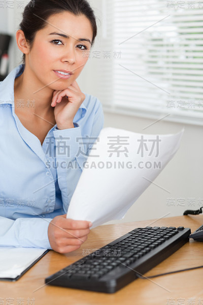有魅力的女人摆姿势，同时拿着一张纸
