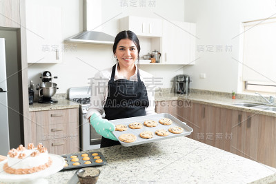 迷人的女糕点厨师拿着饼干烘焙