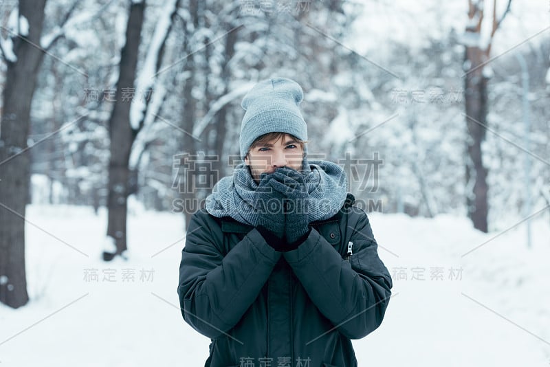 一个年轻人在雪地里散步时暖手的肖像