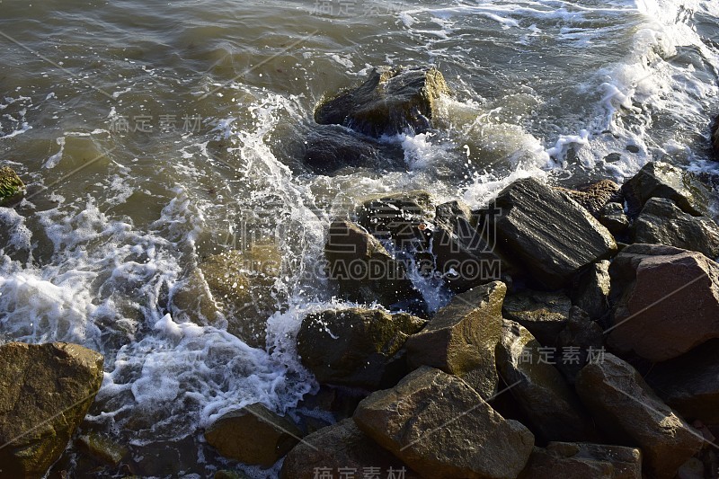 海岸上的海浪和岩石。潮湿的石头和海浪