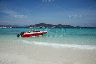 湛蓝的海岸上有一艘摩托艇。红船。沙滩上的小船。