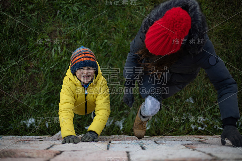 妈妈教儿子爬上一面墙的照片