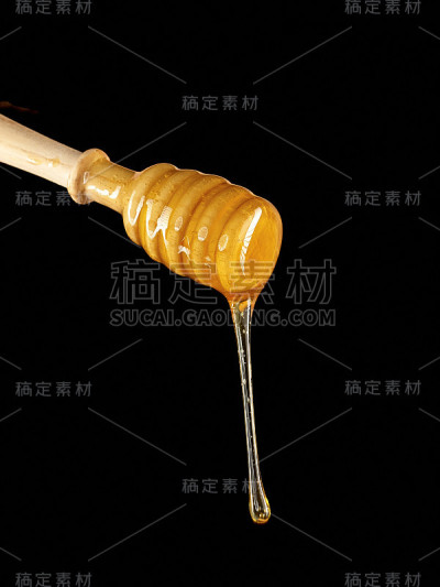 手握木勺，蜂蜜孤立在黑色