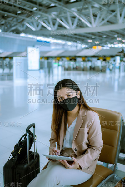 亚洲商务女乘客在机场使用她的数字平板电脑。