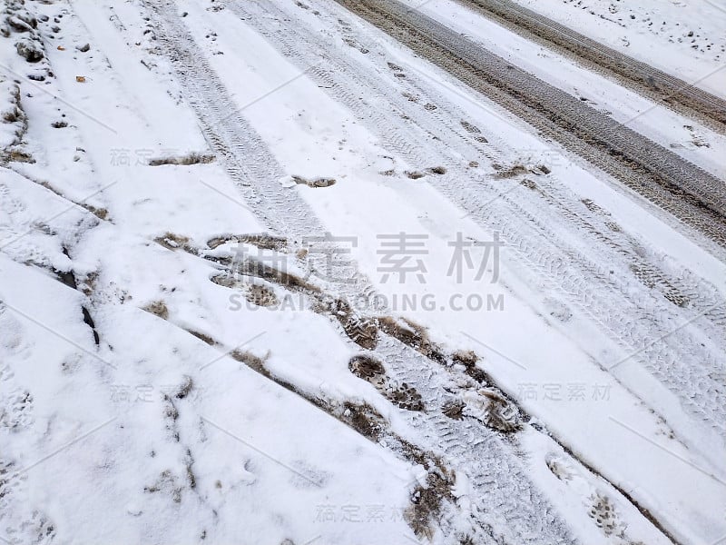 积雪下的道路上留下了汽车的痕迹。