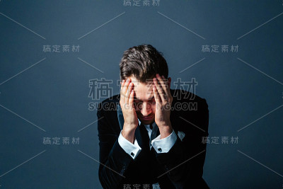 一个年轻英俊的男人的肖像，穿着西装，心烦意乱，手放在头上