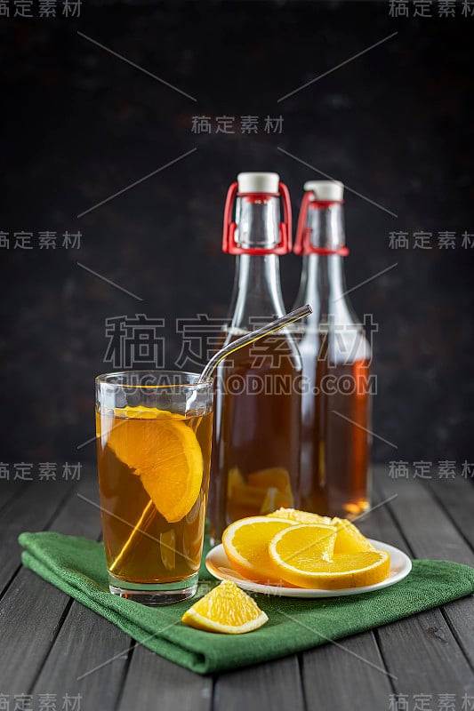 康普茶超级食品益生菌茶饮料在玻璃罐与橙色在黑暗的背景。绿色纺织