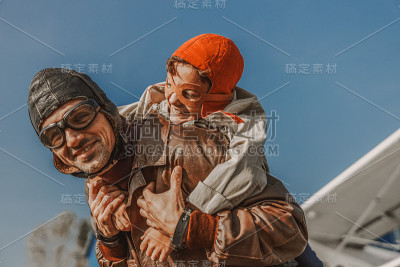 微笑的父亲在飞行员帽有乐趣的孩子