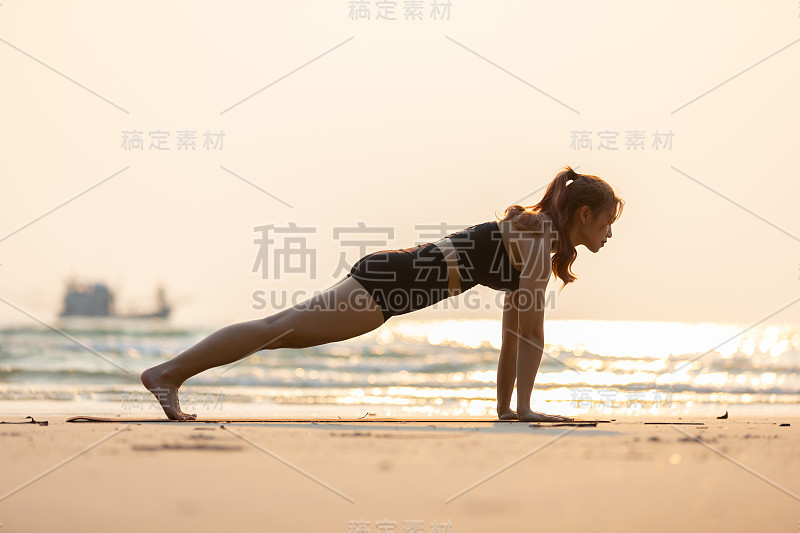 亚洲年轻女子练习瑜伽平板支撑或Phalakasana Pose在沙滩上日落美丽的海洋在热带岛屿，感觉