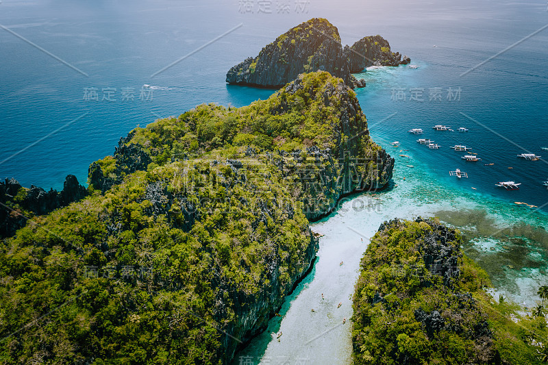 无人机拍摄的浅水热带大、小泻湖入口，游客乘坐皮划艇，周围是锯齿状的石灰岩喀斯特悬崖。菲律宾巴拉望的厄