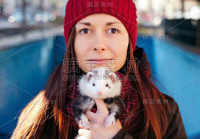 一个可爱的雪貂和它的女主人在户外的肖像