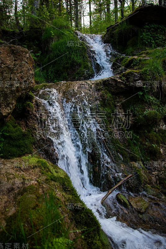 美丽的高山雨林瀑布与快速流动的水和岩石，长时间暴露。自然季节性的户外旅游背景与阳光时兴