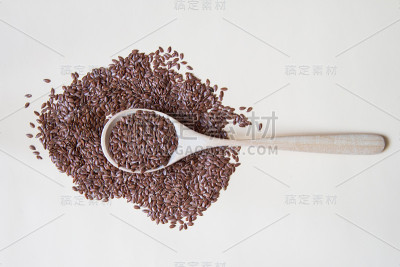 木勺上的亚麻籽米色背景俯视图。