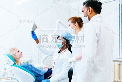 多种族牙科小组检查病人的牙齿x光。牙科诊所的概念