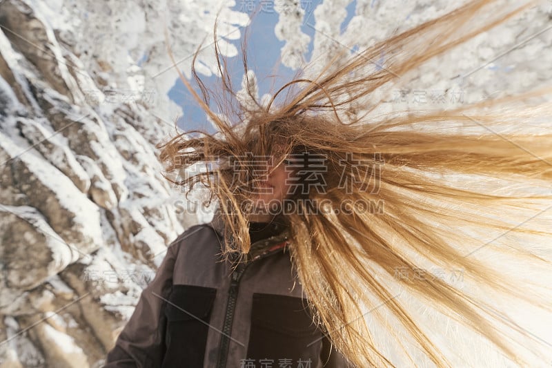 美丽的冬日画像下的年轻女子，白雪覆盖的杉树和悬崖，漂亮的微笑，长长的头发，阳光灿烂的冬日