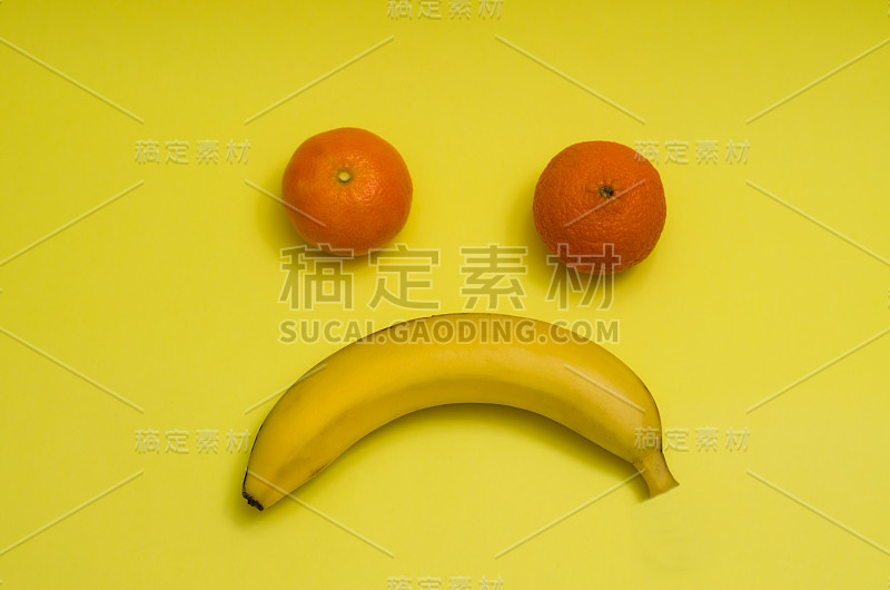 悲伤的水果嘴。香蕉和两个橘子
