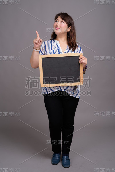 工作室拍摄的成熟美丽的亚洲女商人在灰色的背景