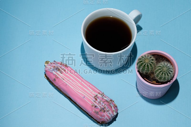 美味的泡芙，一杯黑咖啡，蓝色背景上的仙人掌。极简主义风格的食物。现代早餐概念