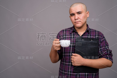 工作室拍摄的年轻亚洲秃头商人穿着格子衬衫，以灰色背景